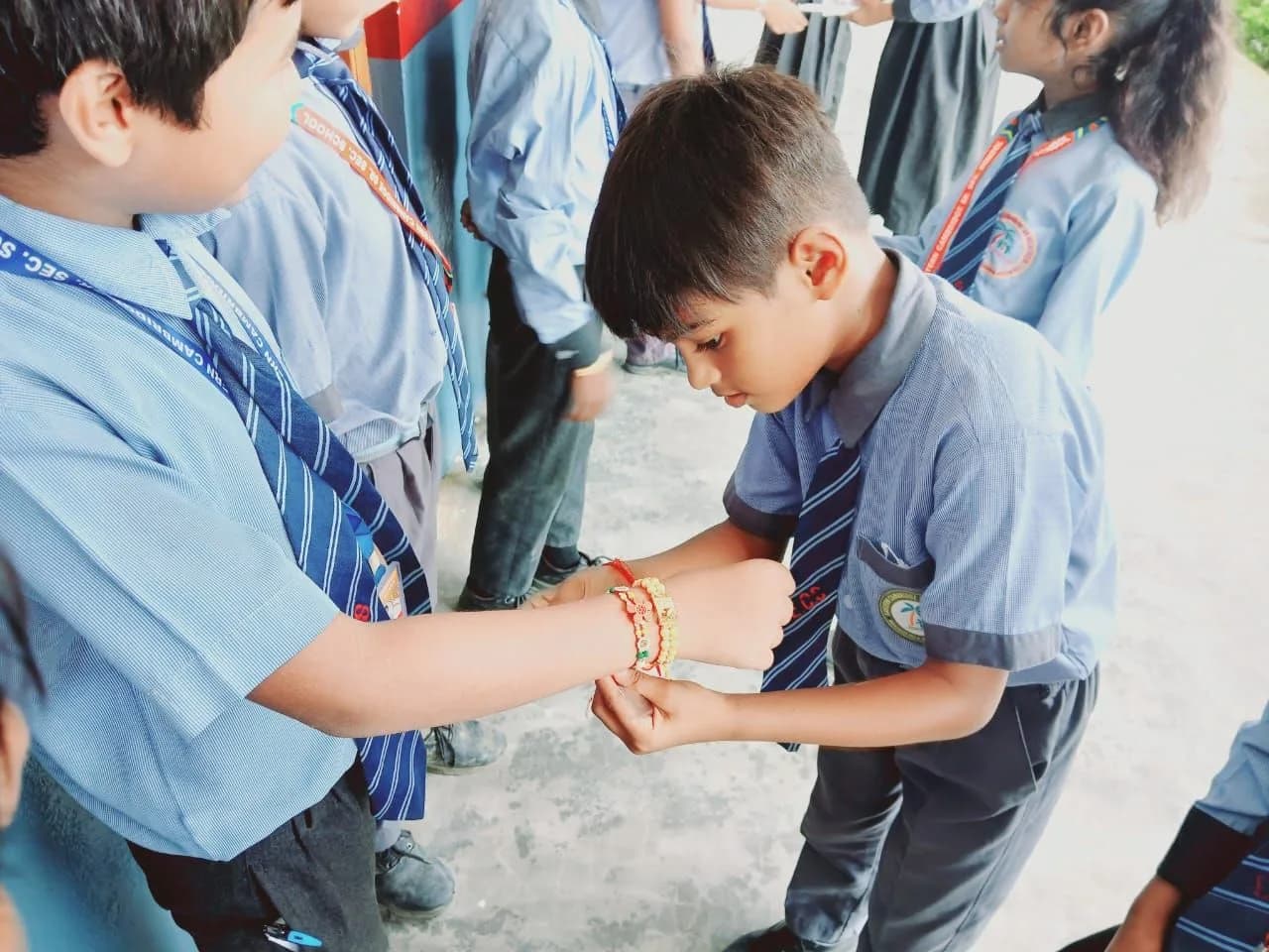 A student tying a rakhi on Raksha Bandhan