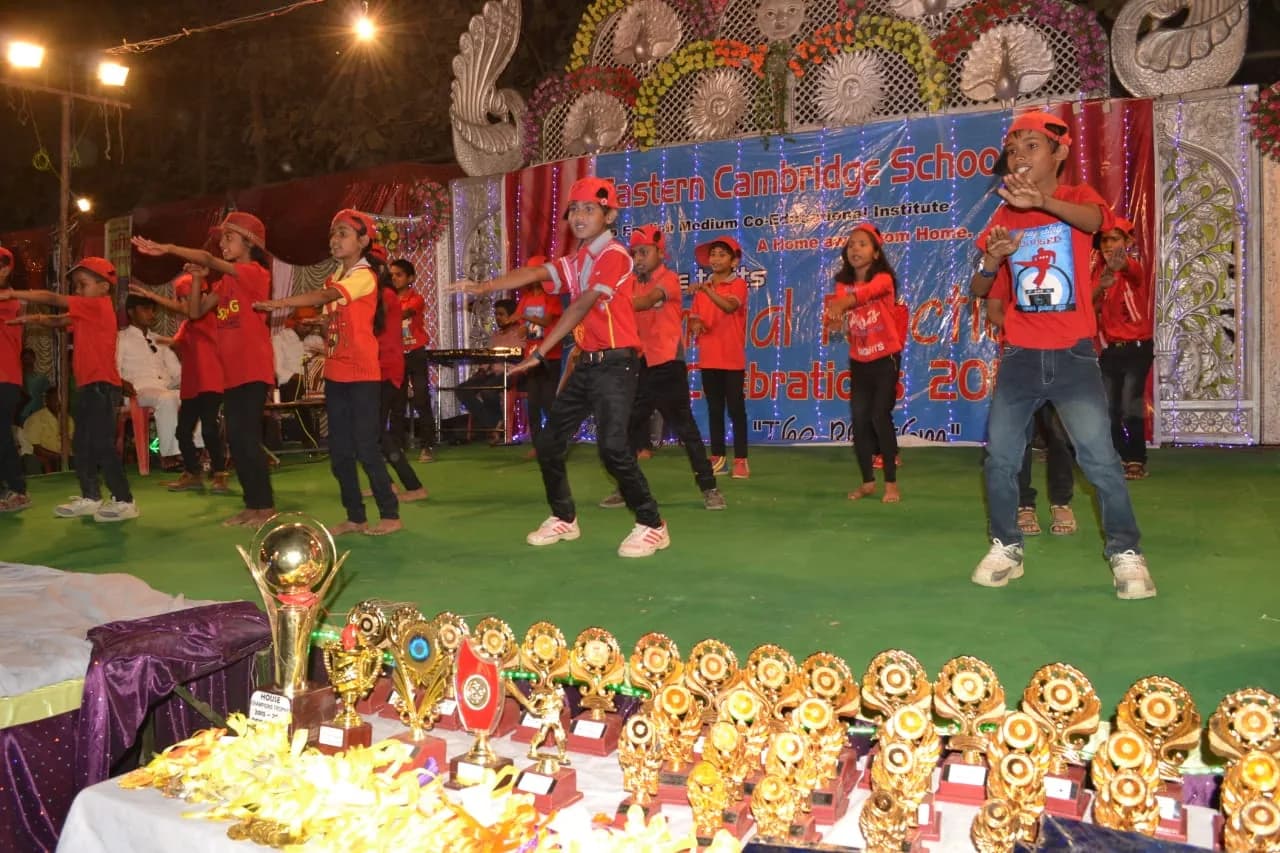 Students dancing on stage beside a table of trophies
